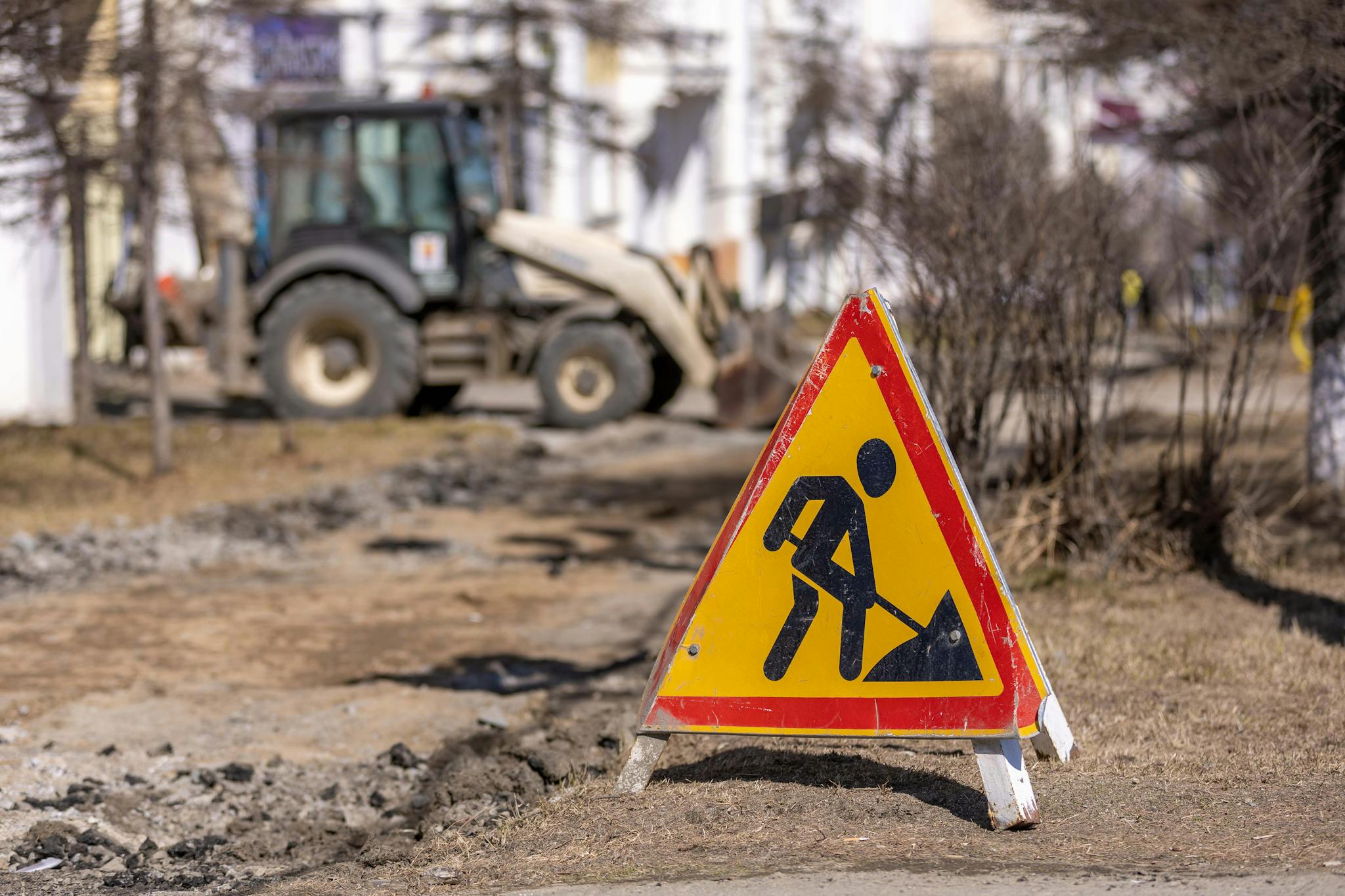 A bright safety warning sign at a road construction site with visible cautionary symbols.